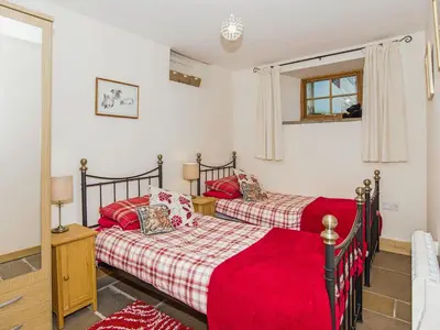 two beds in a bedroom with red sheets at Bramble Cottage - 27978 in Whalley