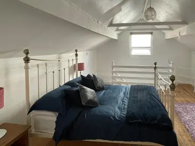 a bedroom with a bed with a blue comforter at The Cottage At Stanley Villa in Southport