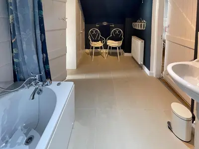 a bathroom with two chairs and a tub and a sink at The Cottage At Stanley Villa in Southport
