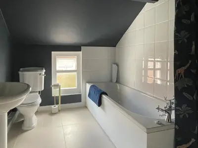 a bathroom with a tub and a toilet and a sink at The Cottage At Stanley Villa in Southport