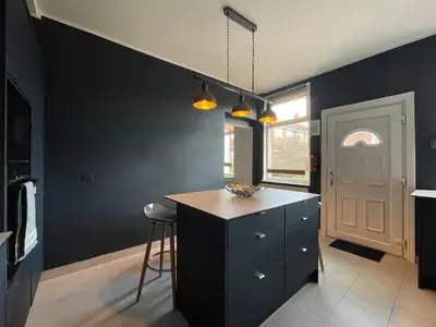 a kitchen with black walls and a counter and a stool at The Cottage At Stanley Villa in Southport