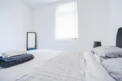 a white bedroom with a bed and a mirror at Beautiful Apartment una - free public parking in Litherland