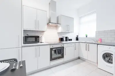 a white kitchen with white cabinets and a washer and dryer at Beautiful Apartment una - free public parking in Litherland