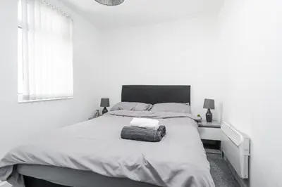 a white bedroom with a large bed and a window at Beautiful Apartment una - free public parking in Litherland