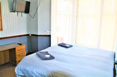 a bedroom with a bed and a desk and a television at Pine Lodge Hotel in Blackpool