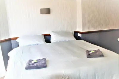 a large white bed with two purple towels on it at Pine Lodge Hotel in Blackpool