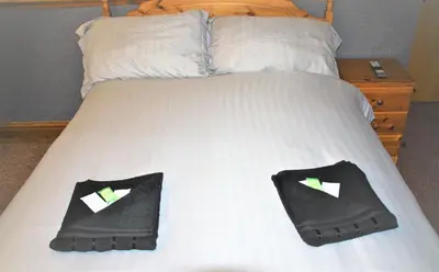 a bed with two black slippers on it with two pillows at Pine Lodge Hotel in Blackpool