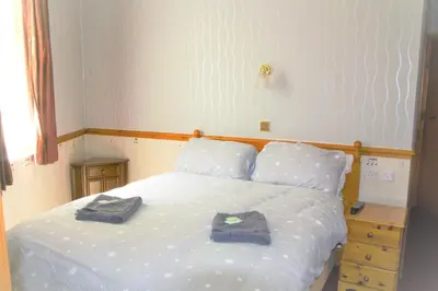 a bedroom with a white bed with two towels on it at Pine Lodge Hotel in Blackpool