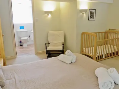 a bedroom with a bed and a crib and a chair at Hope Cottage in Lindale