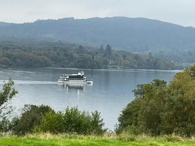 a boat on a lake with mountains in the background at Kents Bank Holiday - Pet Friendly with Bay Views in Grange Over Sands