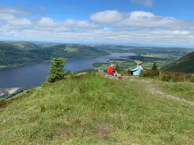 two people sitting on top of a hill overlooking a river at Kents Bank Holiday - Pet Friendly with Bay Views in Grange Over Sands