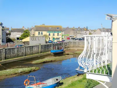 two boats are docked in a river next to a bridge at Cockleshell Cottage in Millom