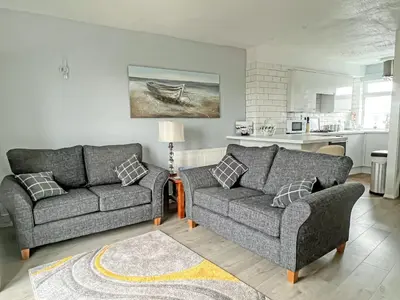 a living room with two couches and a kitchen at Cockleshell Cottage in Millom