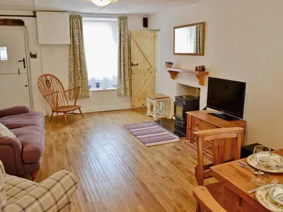 a living room with a couch and a television at Jackdaw Cottage in Baycliff