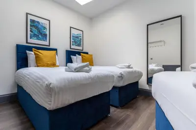 two beds with blue and yellow pillows in a room at Temple Court by UStay Aparthotels in Liverpool