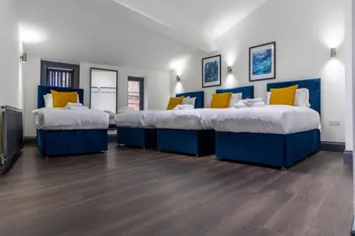 a room with three beds with blue and yellow pillows at Temple Court by UStay Aparthotels in Liverpool