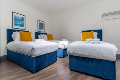 two blue beds with yellow pillows in a room at Temple Court by UStay Aparthotels in Liverpool