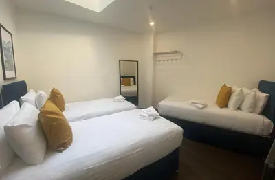 two beds in a room with white and yellow pillows at Temple Court by UStay Aparthotels in Liverpool