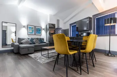 a living room with a dining room table and yellow chairs at Temple Court by UStay Aparthotels in Liverpool