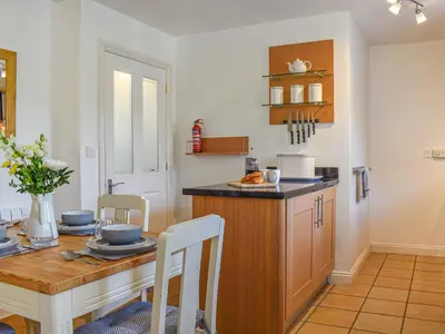 a kitchen with a wooden table and a dining room at Cosy Cottage in Holker