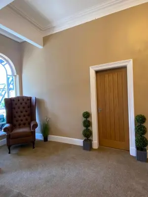 a room with a chair and potted plants next to a door at The New Talbot Hotel in Southport