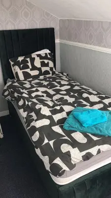 a bed with a black and white comforter and pillows at B&B Runway Blackpool - Minutes From Winter Gardens - Dog Friendly - Exceptionally Quiet - Very Close H&A Social Club in Blackpool