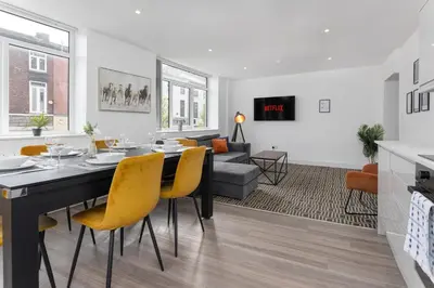 a dining room and living room with a table and yellow chairs at Flatzy - 16 Guests 4 En-suite Central Apartment A in Liverpool
