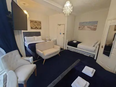 a hotel room with a bed and a couch and chairs at Harriette's Guest House in Blackpool