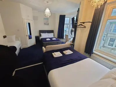 a hotel room with two beds and a couch at Harriette's Guest House in Blackpool