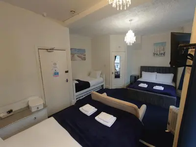 a small room with two beds and a couch at Harriette's Guest House in Blackpool