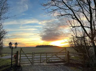 a fence with a gate and a sunset in the background at Rural Family Farmhouse with Countryside views in Southport