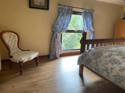 a bedroom with a bed and a chair and a window at Rural Family Farmhouse with Countryside views in Southport