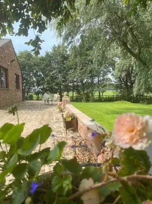 a garden with flowers and a brick wall and a building at Rural Family Farmhouse with Countryside views in Southport
