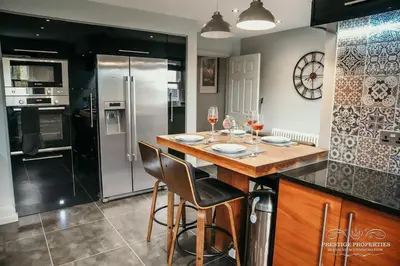 a kitchen with a island with a bar with two chairs at Princes st by Prestige Properties SA in Ulverston