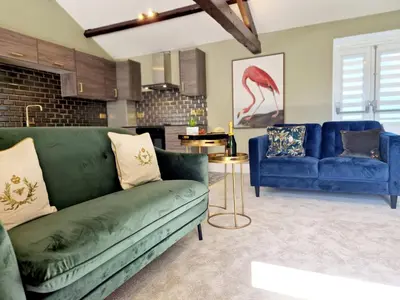 a living room with a green couch and two blue couches at The Cruck in Preston