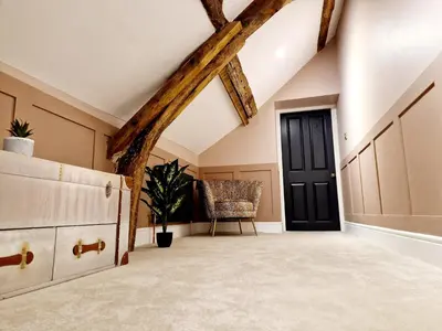 an attic room with a black door and a chair at The Cruck in Preston
