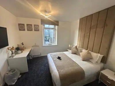 a bedroom with a large bed with a desk and a window at Luxe Hotel Blackpool in Blackpool