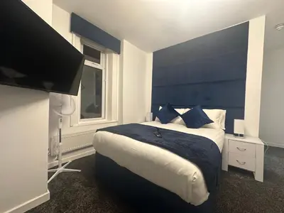a bedroom with a large bed with a blue headboard at Luxe Hotel Blackpool in Blackpool