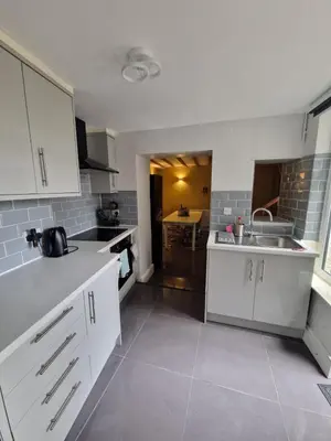 a kitchen with white cabinets and a sink at Courtyard Cottage in Cartmel