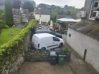 a white van parked next to a wall with trash cans at Courtyard Cottage in Cartmel