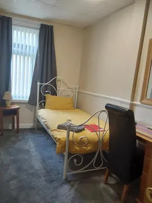 a bedroom with a bed with a yellow pillow and a window at Bianca Guesthouse in Blackpool