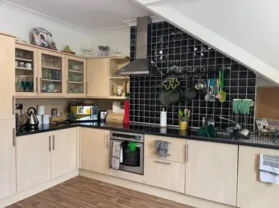 a kitchen with wooden cabinets and a black tile wall at Cosy & Calm Escape by the Sea in Lytham St Annes
