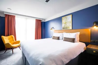 a hotel room with a large bed and a yellow chair at Ropewalks Hotel in Liverpool