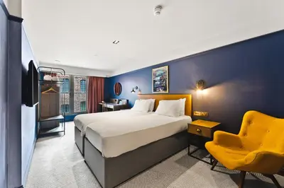 a hotel room with a bed and a yellow chair at Ropewalks Hotel in Liverpool
