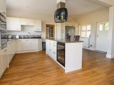 a kitchen with white cabinets and a wooden floor at Homewood in Preston