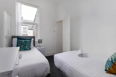 a white bedroom with two beds and a window at Woodbine House - Air Host and Stay - Free parking - Contractor Friendly in Liverpool