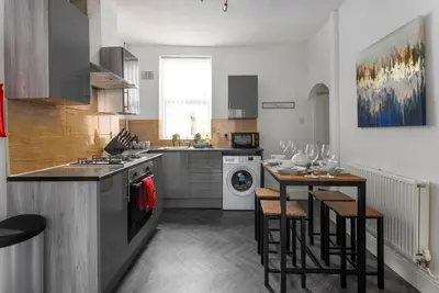 a kitchen with a stove and a table with chairs at Woodbine House - Air Host and Stay - Free parking - Contractor Friendly in Liverpool