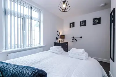 a white bedroom with a bed with white sheets and a window at Charming & Modern 4 bed, ideal for contractors and leisure in Egerton