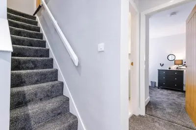 a staircase in a home with white walls and gray carpet at Charming & Modern 4 bed, ideal for contractors and leisure in Egerton