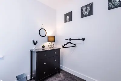 a bedroom with a dresser and a lamp on a wall at Charming & Modern 4 bed, ideal for contractors and leisure in Egerton
